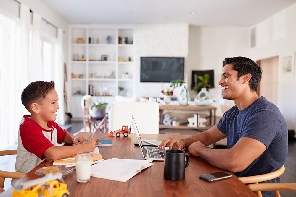 father and son sit at kitchen table laughing