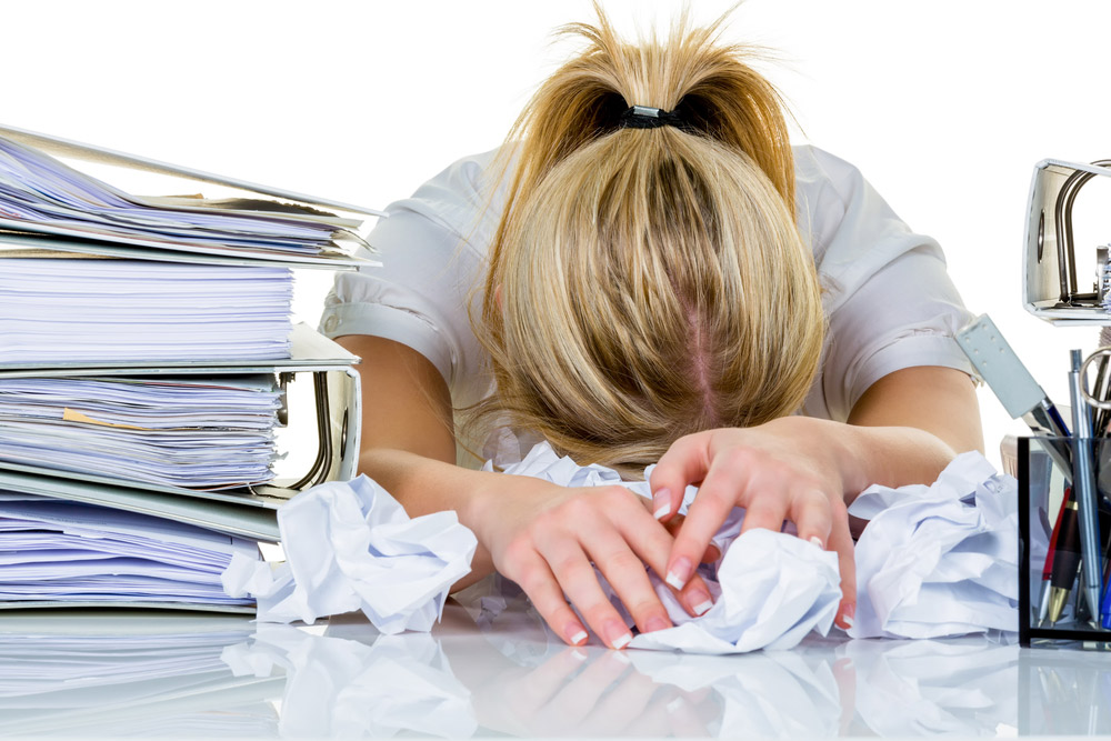 woman with her head on the desk in frustration